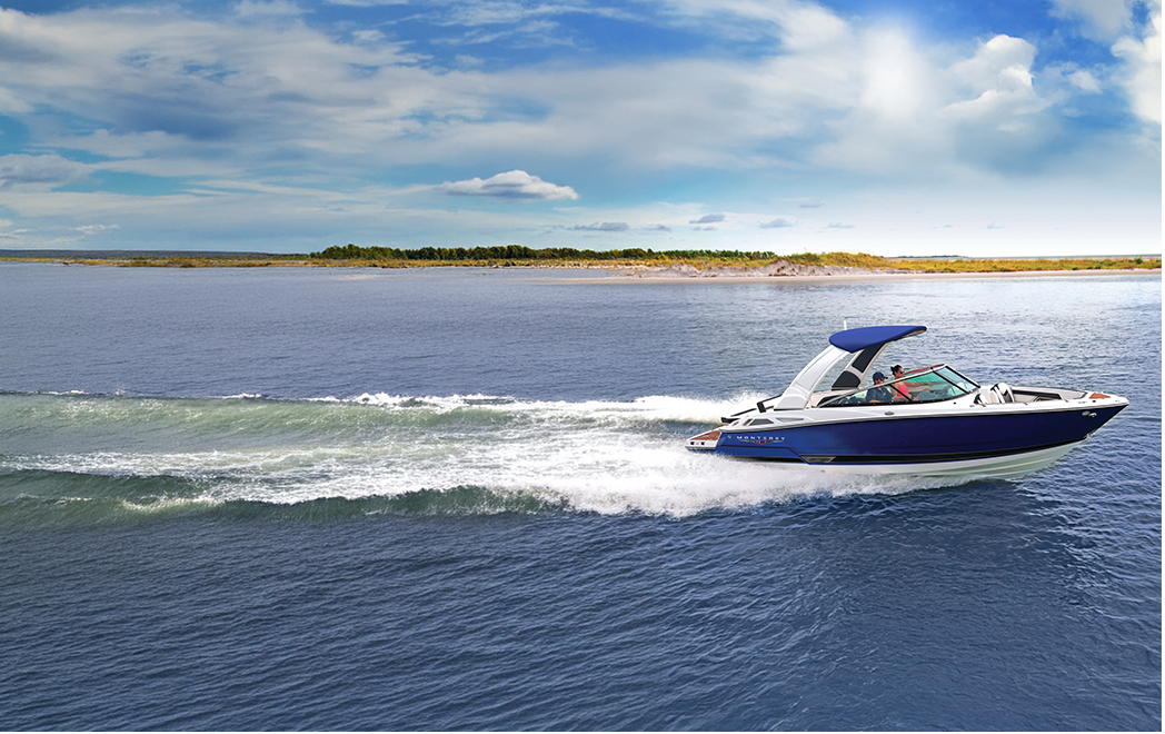 Boat speeding across a wide body of water with a clear blue sky.